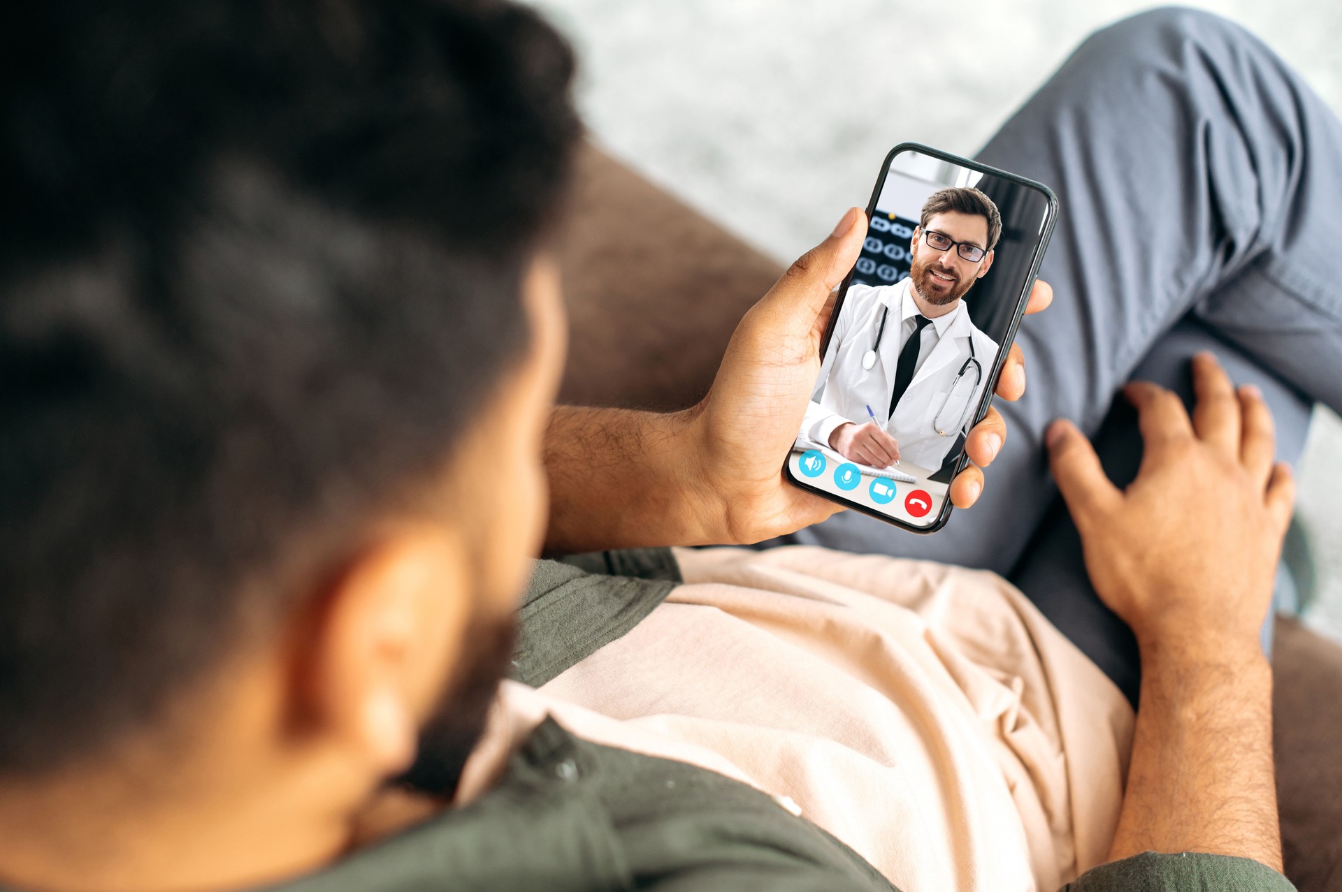 Remote medical consultation. On the phone screen, a Caucasian professional doctor of general medicine, conducts an online consultation with his patient, listens to complaints, prescribes treatment